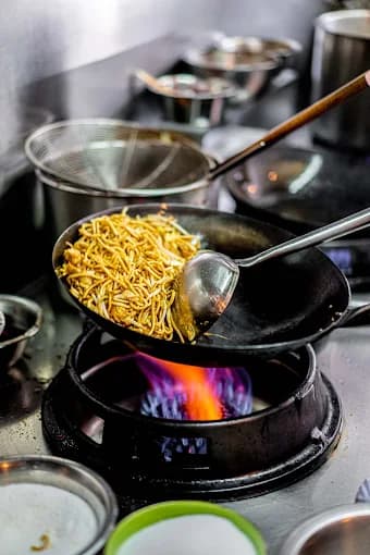 Nudeln werden im Wok über offener Flamme gebraten