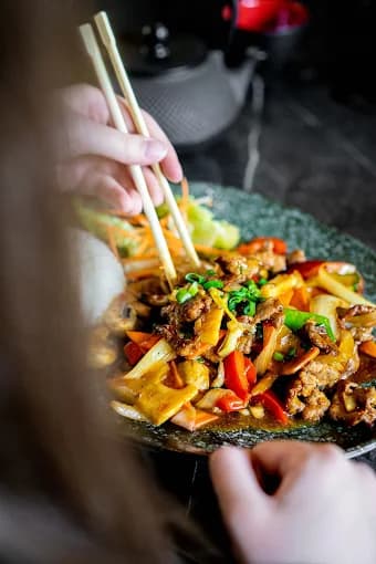 Wok-Teller mit Gemüse, mit Stäbchen gegessen